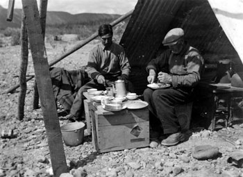 “The dogs don′t get it all.” Pete and Arthur Anderson enjoying a meal of freshly-caught fish.