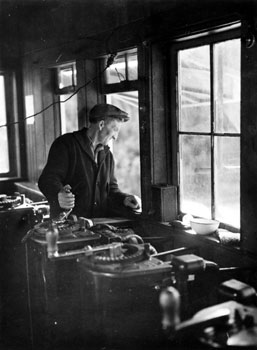 Le treuilliste Hans Oiom actionne une manette dans la salle des treuils de la Yukon Consolidated Gold Company (YCYG), drague no 3 à Dawson, 1938.