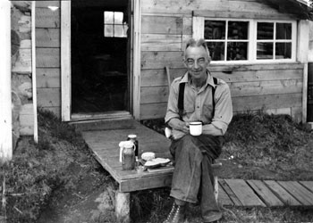 Claude in front of cabin enjoying his tea.